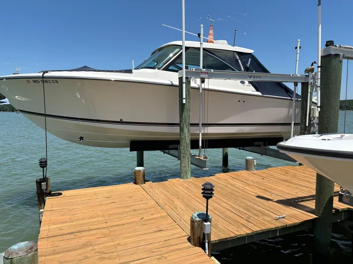  Yacht Photos Pics 2017 Pursuit DC 325 Dual Console boat on lift at wooden dock.