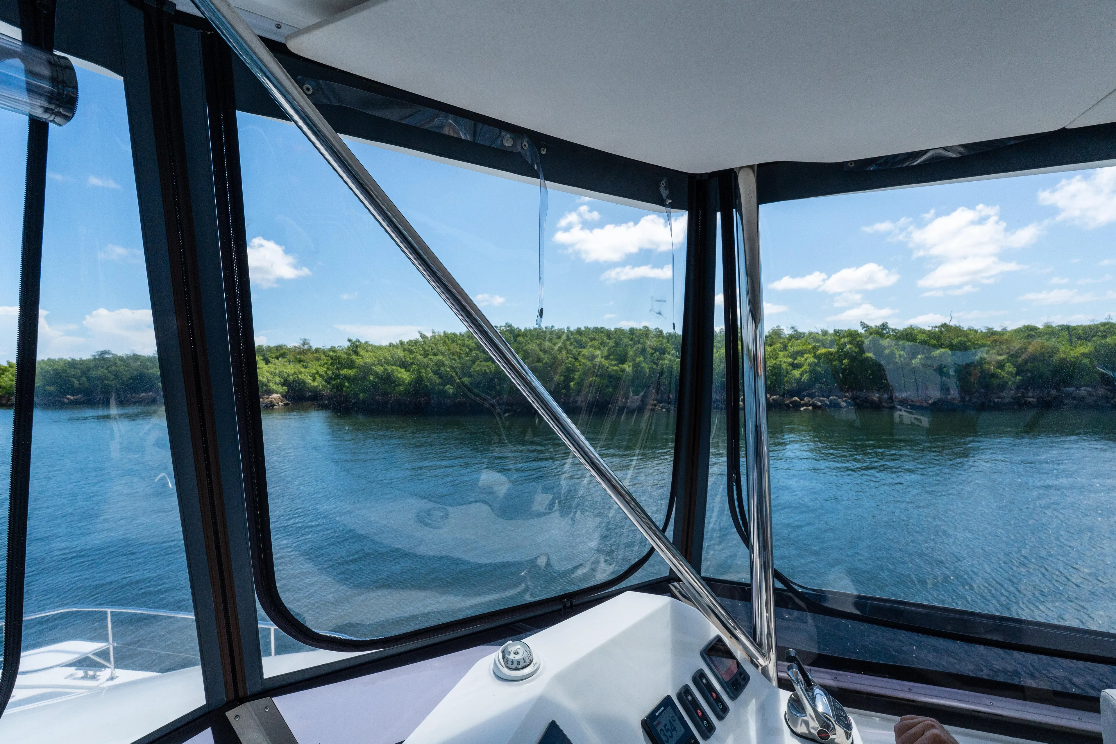Breathe Yacht Photos Pics View from inside a 2020 Leopard 53 Powercat, overlooking serene water and lush greenery.