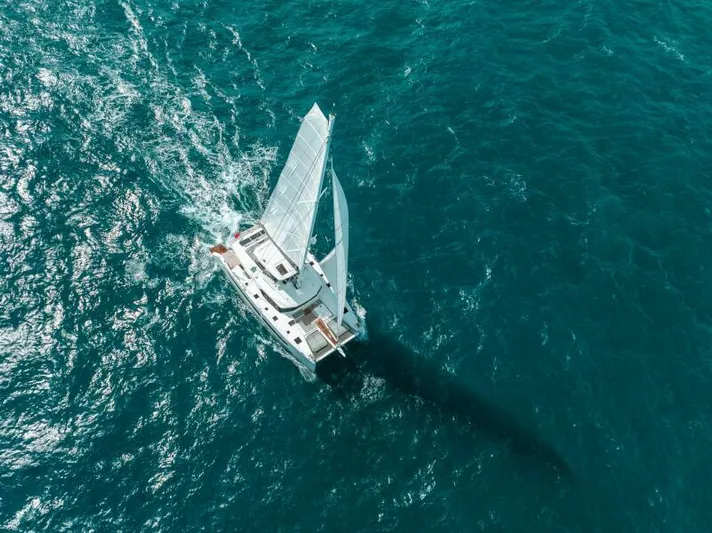 Roamance Yacht Photos Pics Aerial view of 2022 Fountaine Pajot Alegria 67 sailing on open ocean waters.