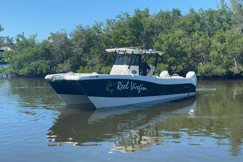  Yacht Photos Pics 2024 World Cat 325 CC boat navigating a calm river, surrounded by lush greenery.