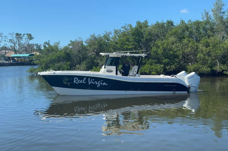  Yacht Photos Pics 2024 World Cat 325 CC boat on calm water, surrounded by lush greenery.