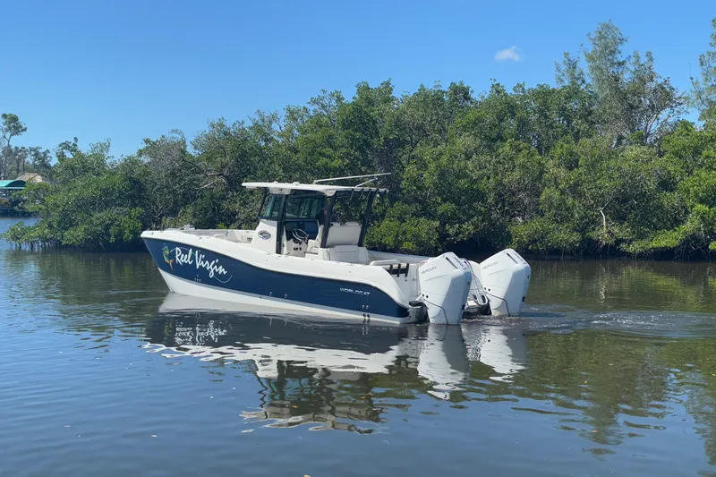  Yacht Photos Pics 2024 World Cat 325 CC boat on calm water, surrounded by lush greenery.