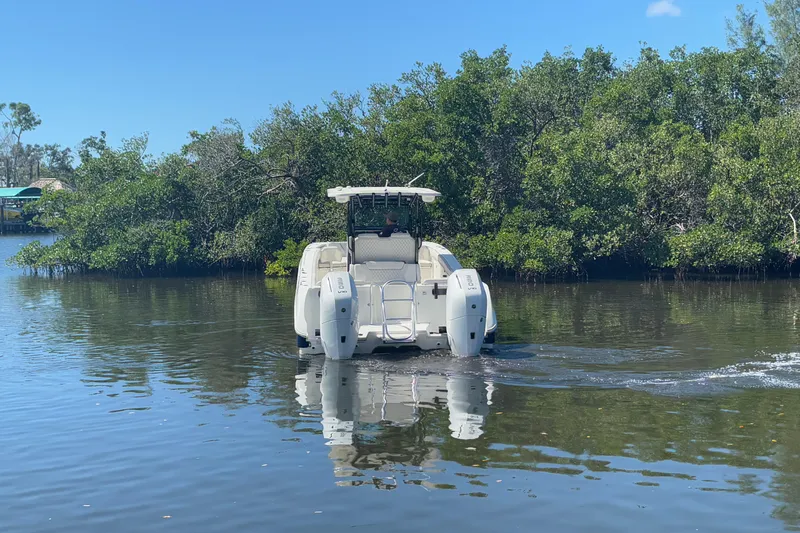  Yacht Photos Pics 2024 World Cat 325 CC boat cruising on calm water near lush greenery.