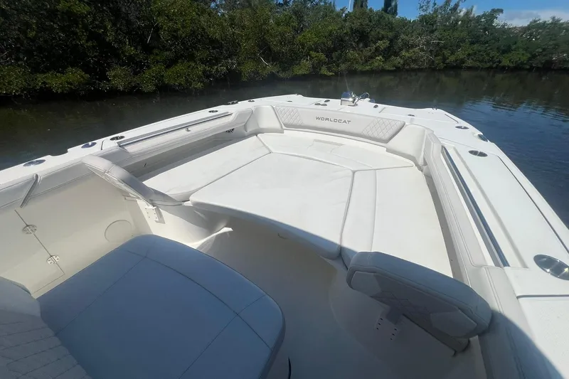  Yacht Photos Pics 2024 World Cat 325 CC boat interior with white seating, near lush greenery.