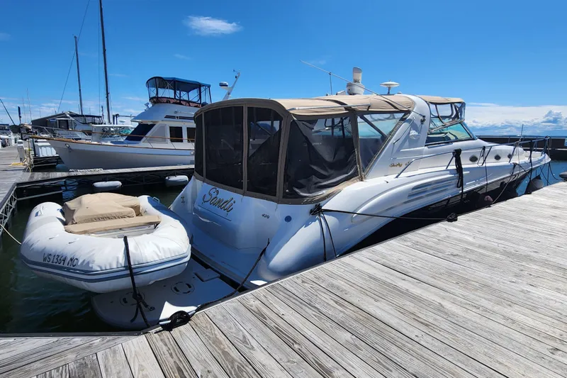 Sandi Yacht Photos Pics 1997 Sea Ray 450 yacht docked with inflatable boat, under clear blue sky.