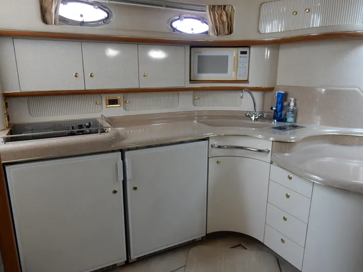 Sandi Yacht Photos Pics 1997 Sea Ray 450 yacht kitchen with white cabinets, microwave, and sink.
