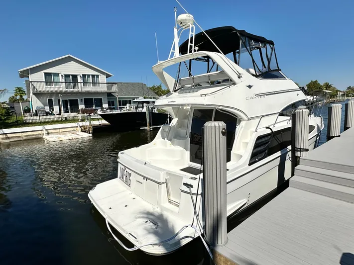 Live Big Yacht Photos Pics 2004 Carver 360 Sport Sedan docked near waterfront home under clear blue sky.