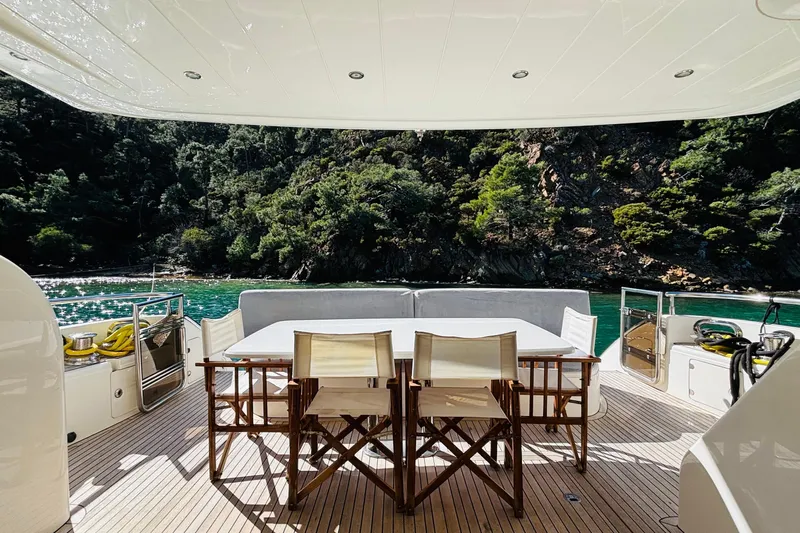  Yacht Photos Pics Luxury yacht deck with dining area, surrounded by lush greenery and turquoise waters. Princess 21M, 2007.