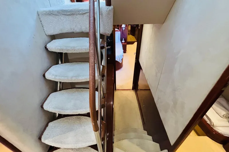  Yacht Photos Pics Curved staircase inside 2007 Princess 21M yacht, featuring carpeted steps and wooden railing.