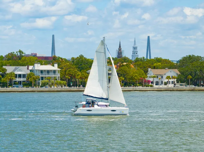 Starry Night Yacht Photos Pics Sailing catamaran Fountaine Pajot Helia 44 on water with cityscape and bridge in background.