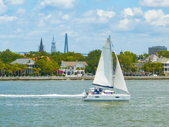 Starry Night Yacht Photos Pics Sailing catamaran Fountaine Pajot Helia 44, 2014, cruising near a scenic waterfront cityscape.