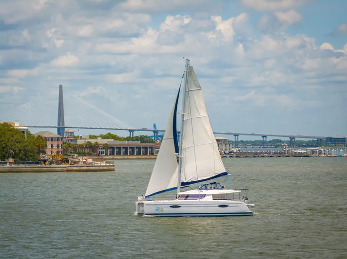 Starry Night Yacht Photos Pics Sailing catamaran Fountaine Pajot Helia 44, 2014, on a scenic waterway with bridge backdrop.