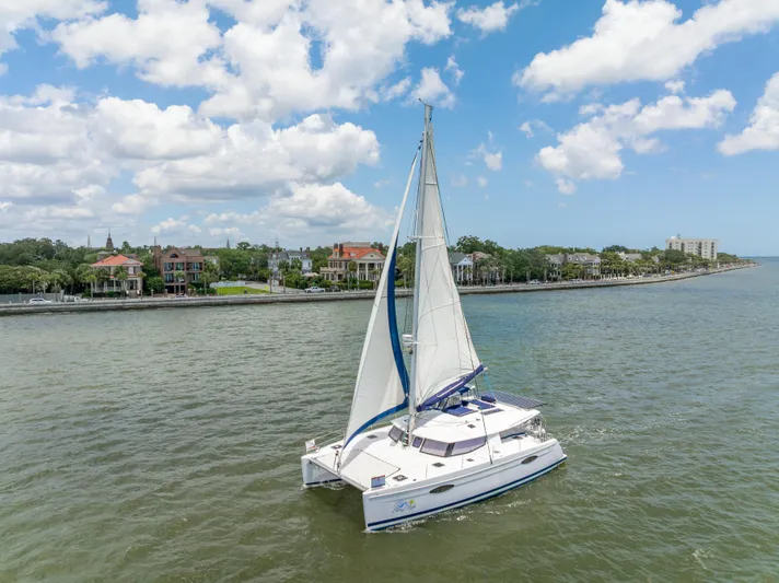 Starry Night Yacht Photos Pics 2014 Fountaine Pajot Helia 44 catamaran sailing near a scenic coastal town.