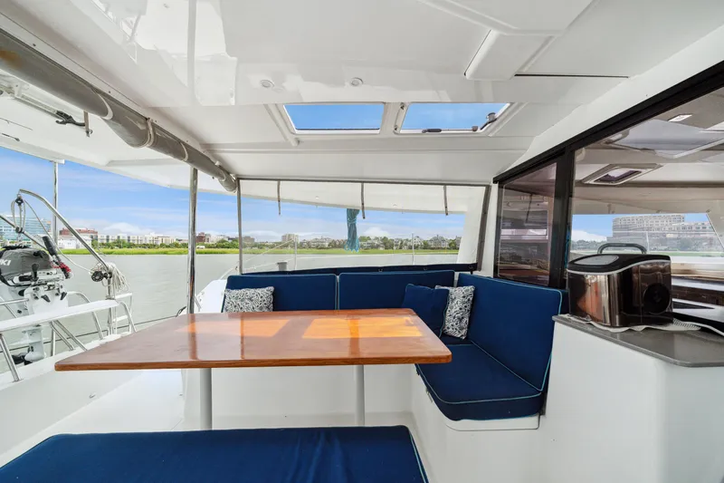 Starry Night Yacht Photos Pics Interior of 2014 Fountaine Pajot Helia 44 catamaran with blue seating and wooden table.
