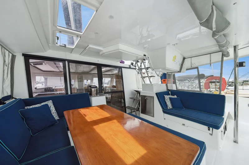 Starry Night Yacht Photos Pics 2014 Fountaine Pajot Helia 44 catamaran interior with blue seating and wooden table.