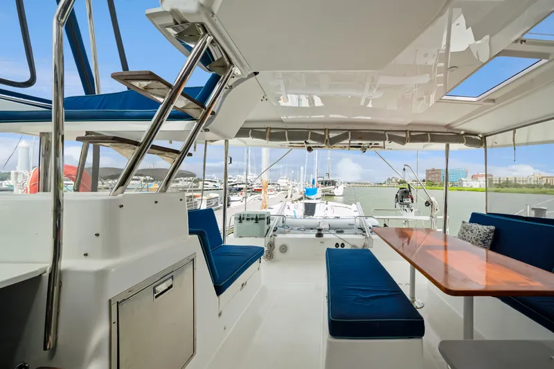 Starry Night Yacht Photos Pics Spacious deck of 2014 Fountaine Pajot Helia 44 catamaran with blue seating and wooden table.