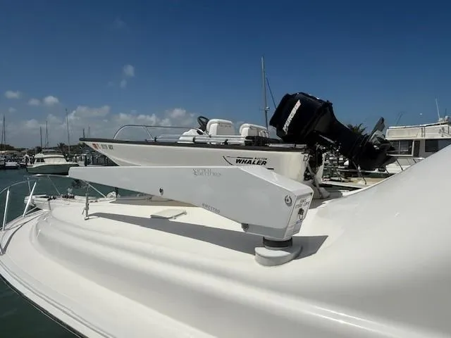 Quite Nice Yacht Photos Pics 2004 Bertram 570 Convertible yacht with a Whaler boat on deck, docked at marina.