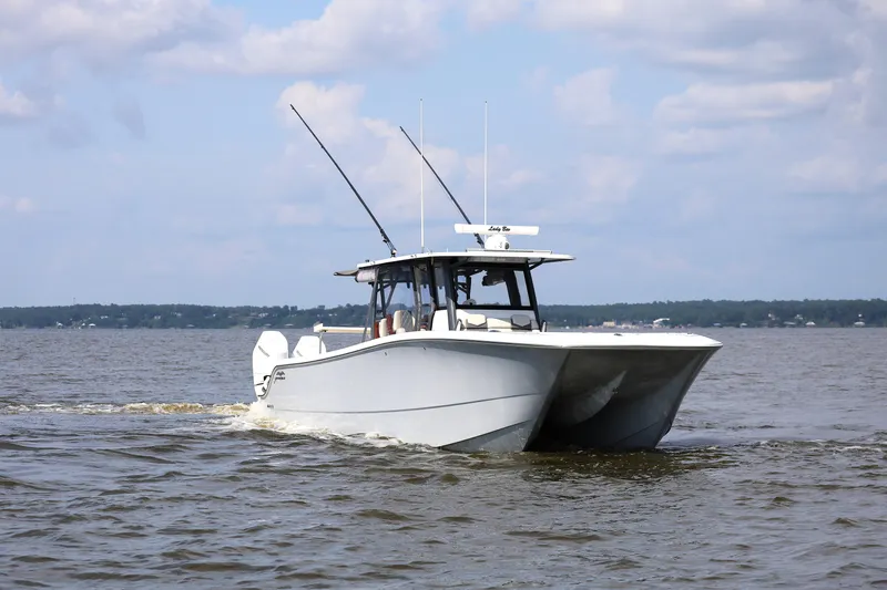  Yacht Photos Pics 2022 Invincible 46 Catamaran cruising on open water under a cloudy sky.