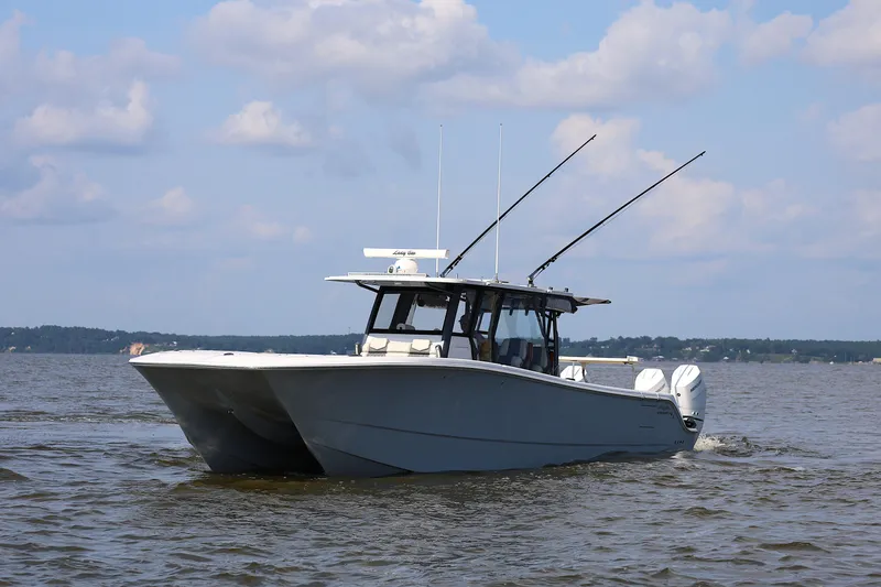  Yacht Photos Pics 2022 Invincible 46 Catamaran cruising on a calm lake under a partly cloudy sky.
