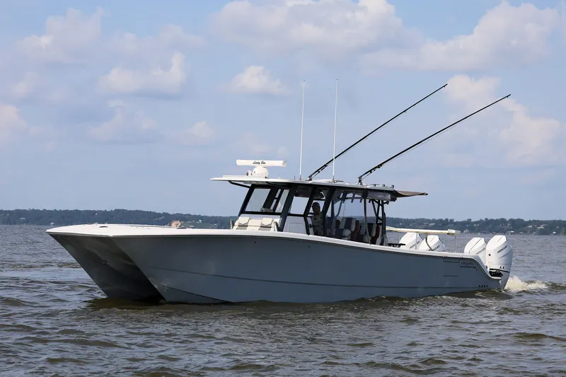  Yacht Photos Pics 2022 Invincible 46 Catamaran cruising on open water under a partly cloudy sky.