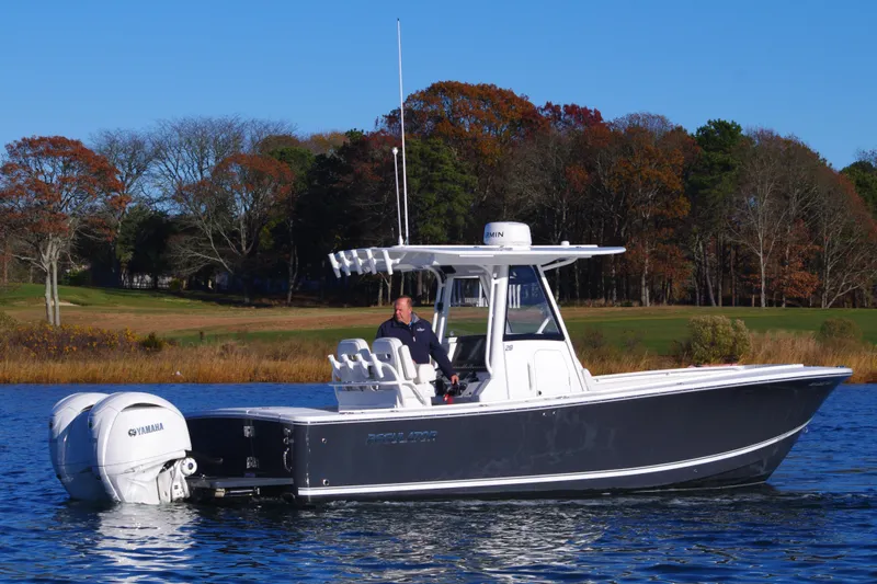  Yacht Photos Pics 2023 Regulator 28 boat on a calm lake with autumn trees in the background.