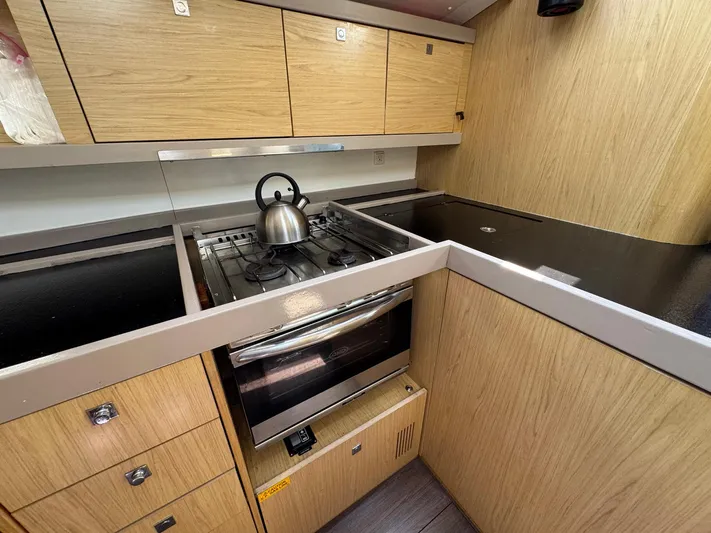 Halcyon Yacht Photos Pics Modern kitchen in 2017 Beneteau Oceanis 48 yacht with stove and wooden cabinetry.