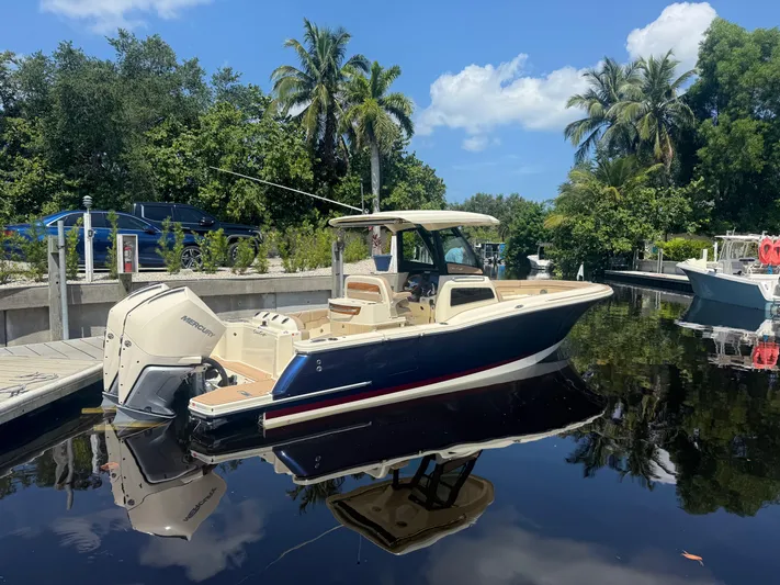  Yacht Photos Pics 2025 Chris-Craft Catalina 28 boat docked on a sunny day, surrounded by lush greenery.