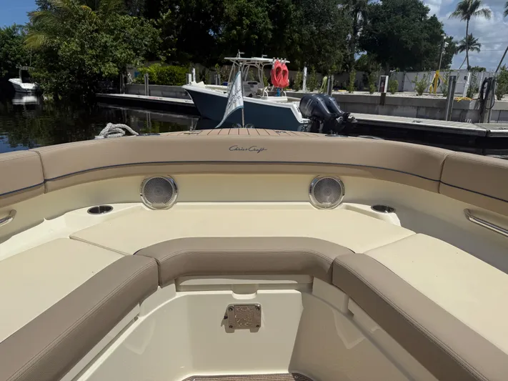  Yacht Photos Pics 2025 Chris-Craft Catalina 28 boat interior with beige seating and speakers, docked by lush greenery.