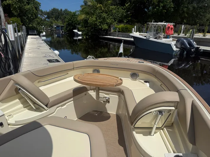 Yacht Photos Pics 2025 Chris-Craft Catalina 28 boat interior with seating and table, docked by a serene waterway.