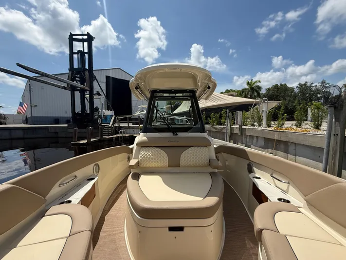  Yacht Photos Pics 2025 Chris-Craft Catalina 28 boat interior with beige seating, docked under a sunny sky.