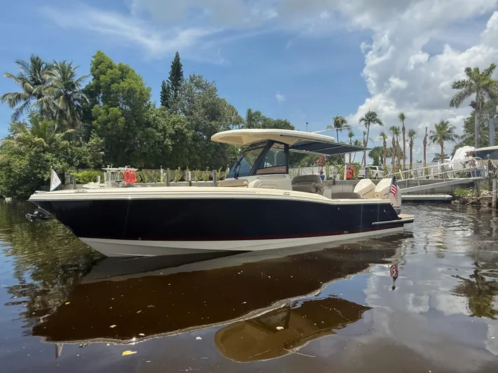 Yacht Photos Pics 2025 Chris-Craft Catalina 28 boat on calm water, surrounded by lush greenery and palm trees.