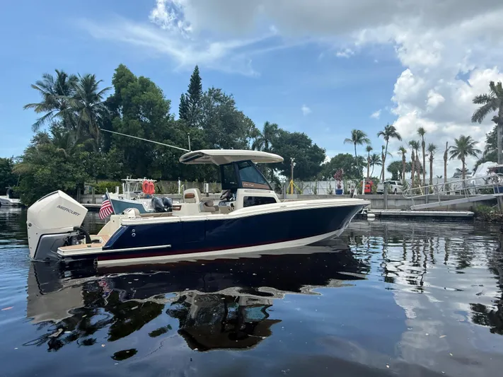  Yacht Photos Pics 2025 Chris-Craft Catalina 28 boat on calm water, surrounded by palm trees.