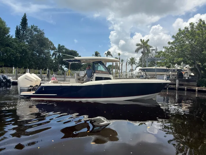  Yacht Photos Pics 2025 Chris-Craft Catalina 28 boat on calm water, surrounded by trees and a cloudy sky.