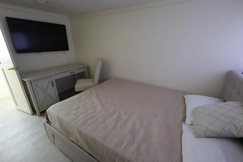 Ocean Drive Yacht Photos Pics Bedroom interior of 1988 Broward 124 Tri-Deck MY yacht with bed, TV, and desk.