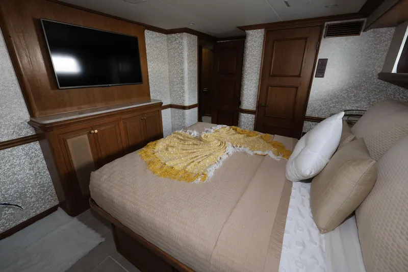 Ocean Drive Yacht Photos Pics Luxurious bedroom in 1988 Broward 124 Tri-Deck MY yacht with TV and elegant decor.