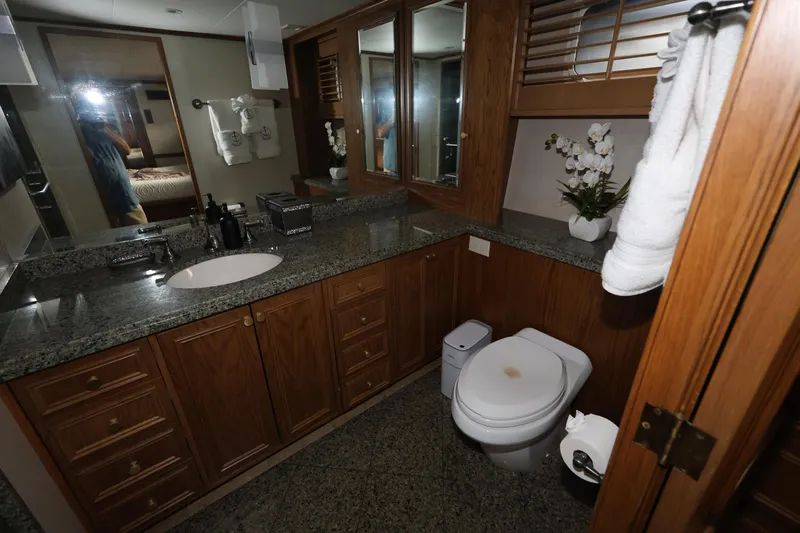 Ocean Drive Yacht Photos Pics Luxurious bathroom in 1988 Broward 124 Tri-Deck MY yacht with granite countertops and wooden cabinetry.