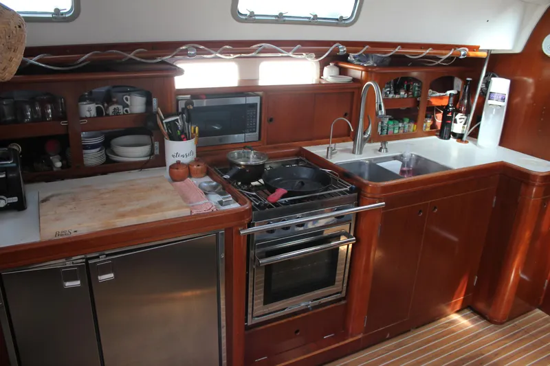 Hawaiian Passage Yacht Photos Pics Interior kitchen of 1997 Beneteau Oceanis 461 yacht with wooden cabinetry and modern appliances.