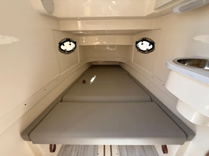  Yacht Photos Pics 2025 Scout 305 LXF cabin interior with cushioned seating and portholes.