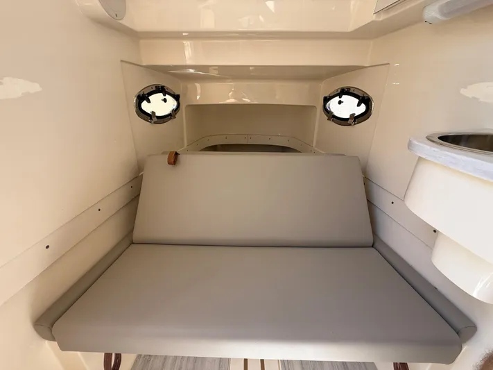  Yacht Photos Pics 2025 Scout 305 LXF cabin interior with cushioned seating and portholes.