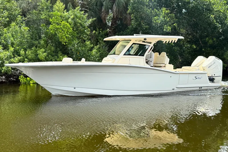  Yacht Photos Pics 2025 Scout 305 LXF boat cruising on a calm river, surrounded by lush greenery.