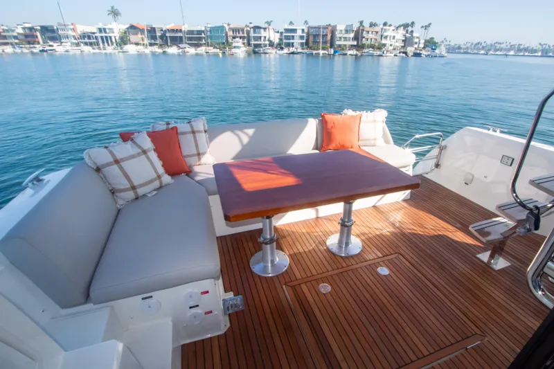 Fantasea Yacht Photos Pics Prestige 460 Fly 2020 yacht deck with seating area and table, overlooking waterfront homes.