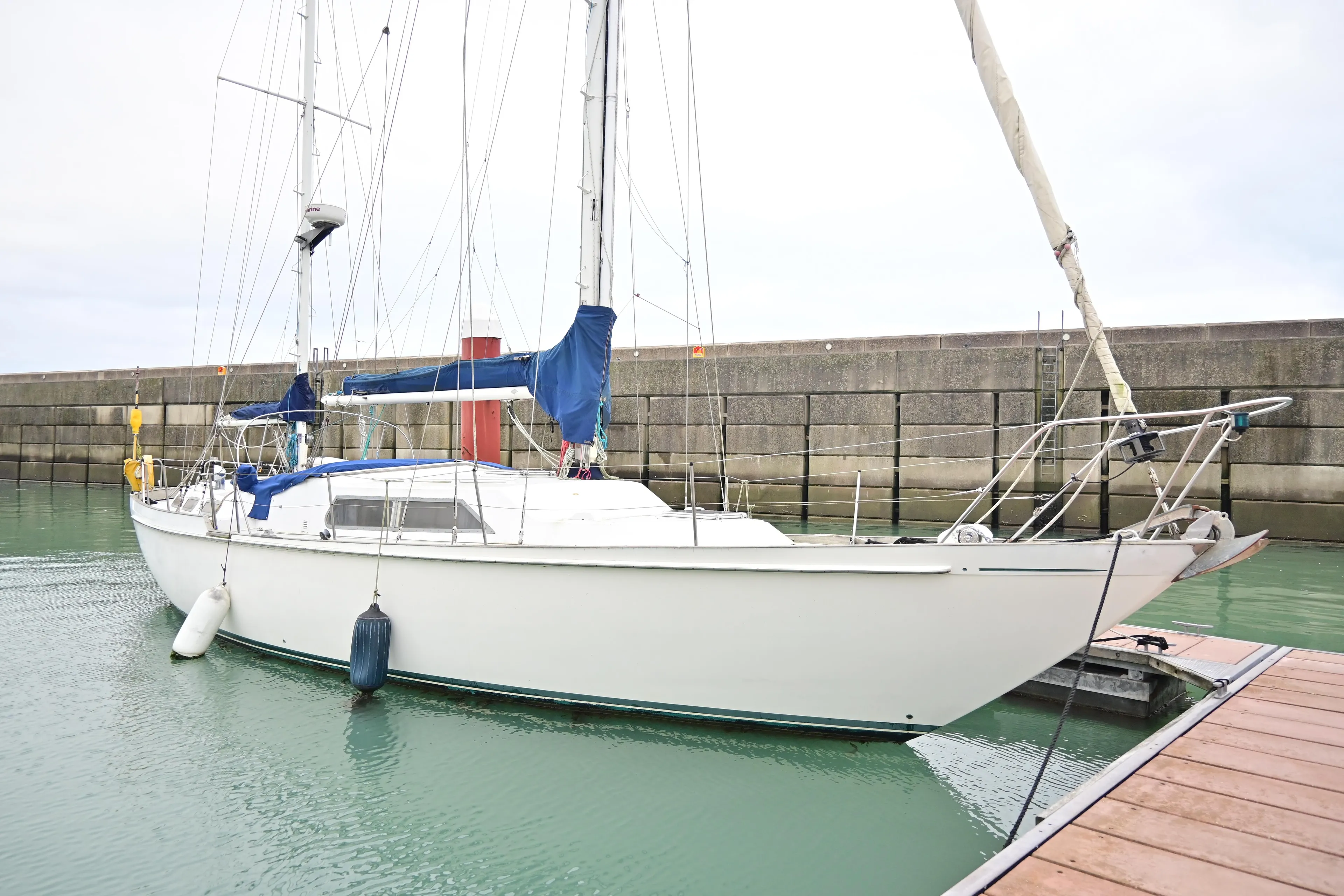 1978 Nicholson 48 Ketch sailboat docked in a marina, featuring blue sail covers.
