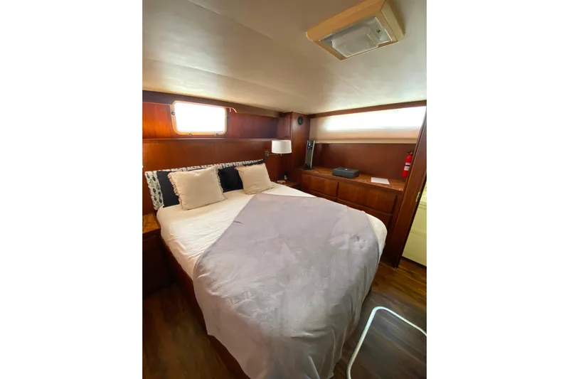  Yacht Photos Pics Cozy bedroom in 1988 Hatteras 40 Double Cabin yacht with wood paneling and soft lighting.