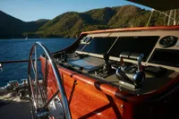Helm of a 2020 Custom Schooner with scenic mountain and lake view.