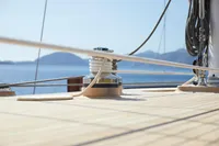 Custom 2020 schooner deck with winch, ropes, and scenic ocean view.