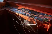 Steering wheel and control panel of a 2020 custom schooner, illuminated by sunlight.