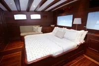Luxurious cabin interior of a 2020 custom schooner with elegant wood finish and cozy bedding.