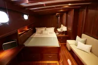 Luxurious 2020 custom schooner cabin with wooden interior, cozy bed, and elegant decor.