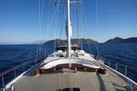 Custom 2020 schooner sailing on open sea with mountainous horizon.