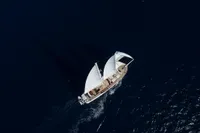 Aerial view of a 2020 custom schooner sailing on deep blue ocean waters.